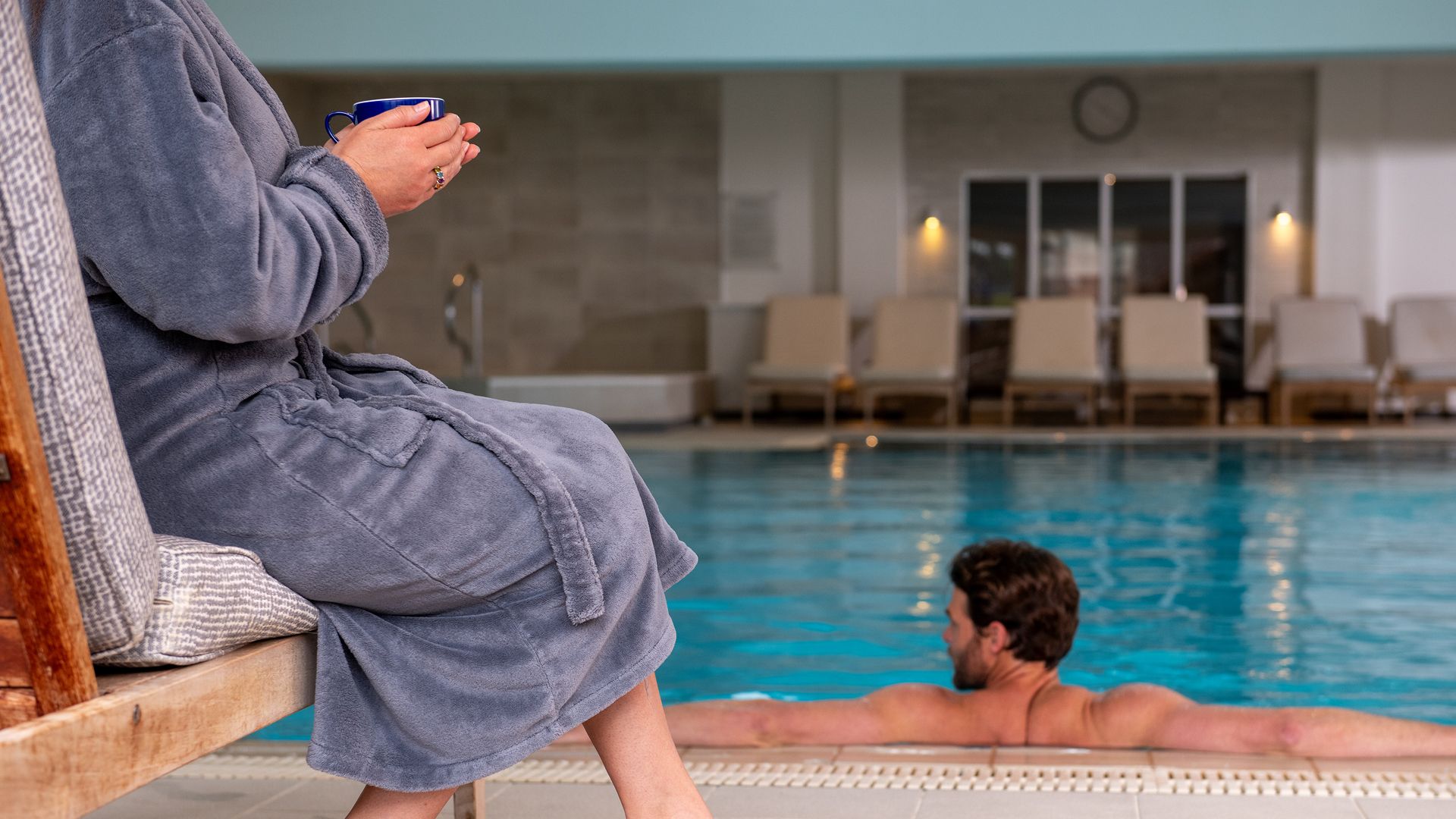 Man in spa pool, woman to the left with a hot drink