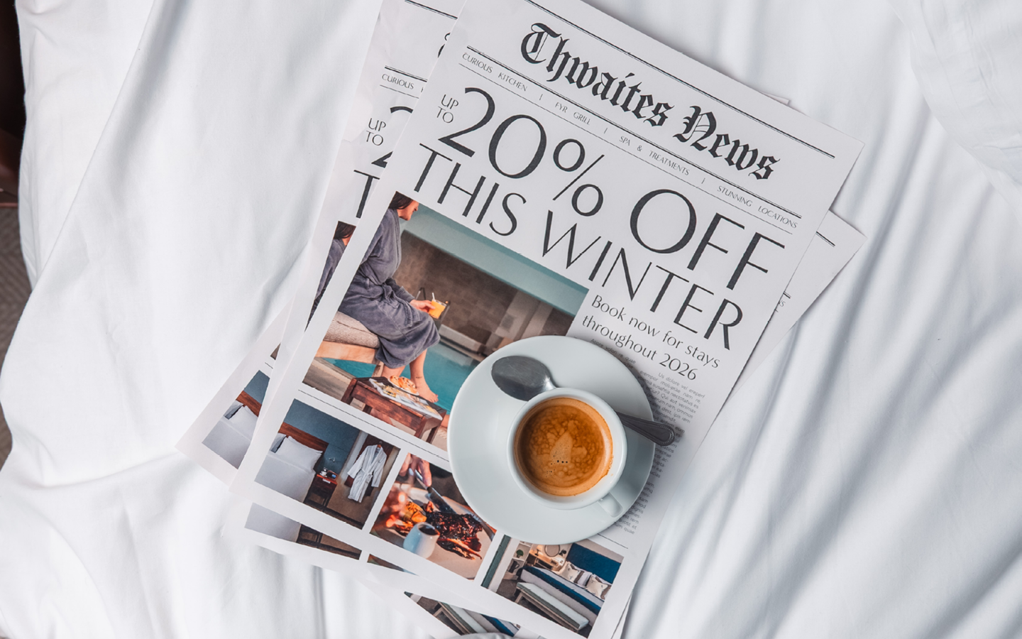 Newspaper and coffee on hotel bed with the headline "Up to 20% off winter sale"