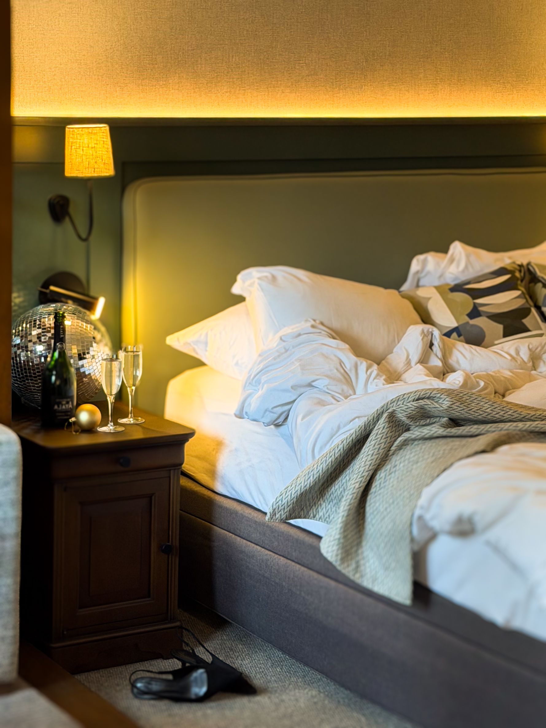 Bedroom with messy bed and glitter ball and champagne on the side