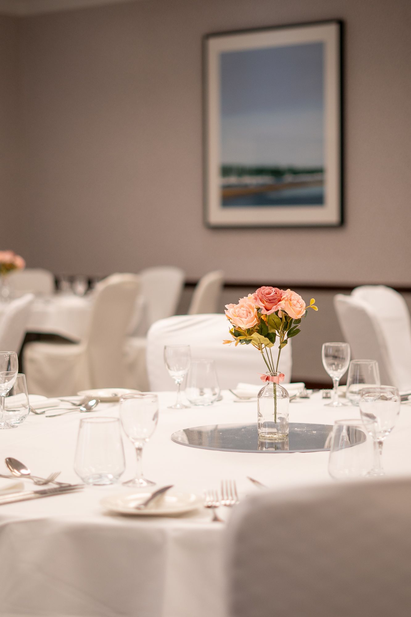 Close up detailed image of table setting with white table cloth and flowers in centre